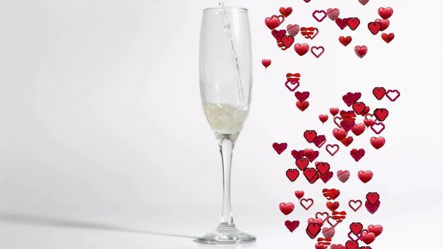 Tall champagne flute receiving pale pouring from above causing red hearts rising beside evoking joy