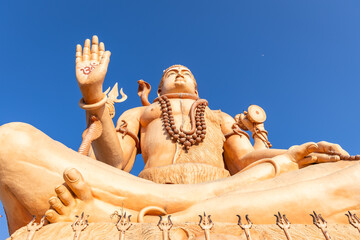 serene shiva idol with traditional attributes under clear sunny sky from low angle