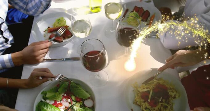 Four diners sharing food at white table golden trail appearing from right threading between glasses