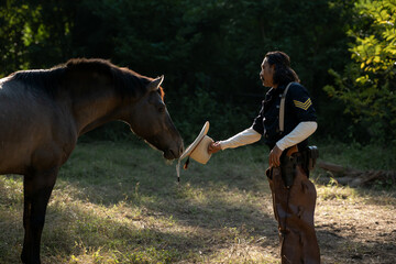 A cowboy gently touching his horse in warm evening light