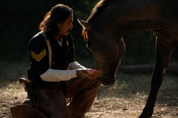 A cowboy gently touching his horse in warm evening light