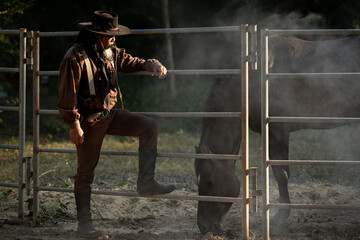A cowboy standing beside his horse in warm evening light, in the horse training time