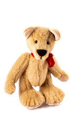 A hand made beige teddy bear wearing a red ribbon around its neck, isolated on a white background