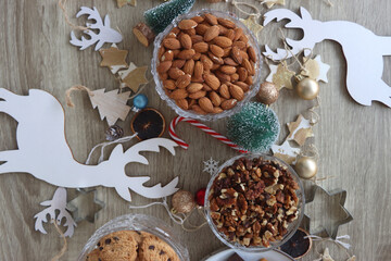 Various Christmas decorations, cookies, chocolate and nuts on wooden background. Flat lay.