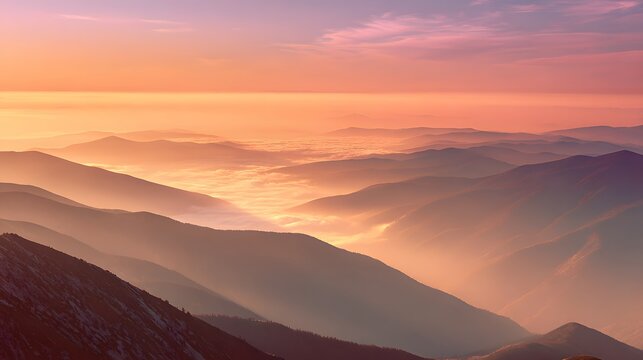 Layered mountain ranges glow with warm light above a valley filled with mist