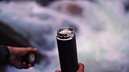 Man Filling Water Bottle from Fresh Mountain Stream - Powered by Adobe