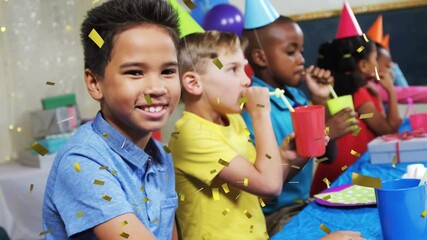Boy in blue shirt smiling while confetti release covering kids wearing party hats at birthday