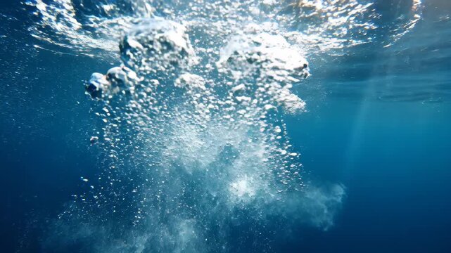 Underwater bubble stream with sun rays illuminating the deep blue ocean