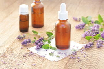 Patchouli essential oil or extract in glass bottle dropper with flowers on wooden table, closeup, natural medicine and healthy skin and body treatment concept