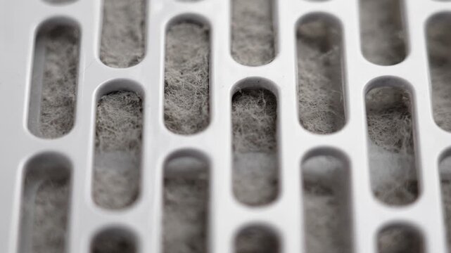 Plastic filter of home ventilation air purifier contaminated with grey house dust fibers