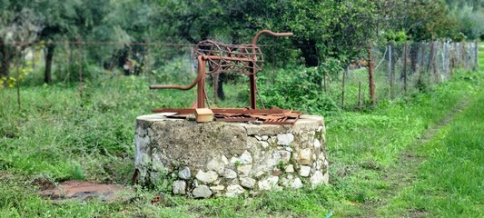 Old Rusty Traditional Water Well in Rural Landscape