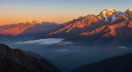 Sunlit peaks of the caucasus mountains at sunrise with fog in the valley