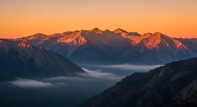Mountains at sunrise with fog in the valley and orange glow on peaks