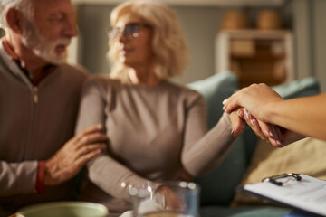 Close up of unrecognizable doctor holding hands with her patient during home visit.