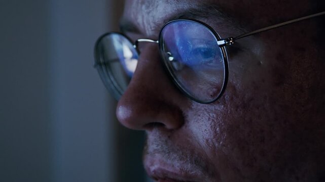 Close-up of disabled programmer coding at night with the code reflecting in his glasses
