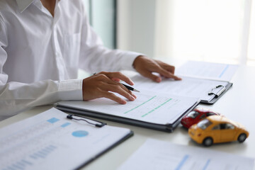 A man signing a contract for a car loan, lease, vehicle registration or insurance policy. Concept for Sales Contract, Financing Agreement, Insurance Policy, Vehicle Registration.