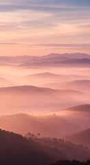 Obraz premium Layers of misty mountains at sunrise with soft pastel colors painting the sky and illuminating the fog
