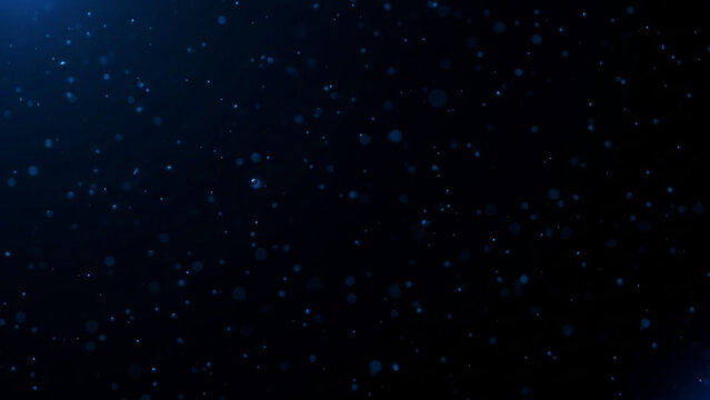 Abstract blue particles floating against a dark background, creating a mesmerizing visual