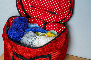 Colourful balls of wool in a red spotted knitting bag, hobby concept