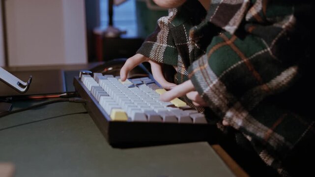 Close-up of a disabled man with limited hand mobility working at a desktop computer in the evening, showing perseverance and inclusion.
