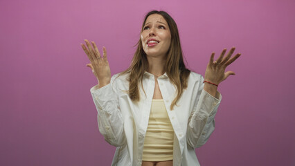 Woman young hispanic raising hands and looking upward with pleading expression, wearing white shirt...