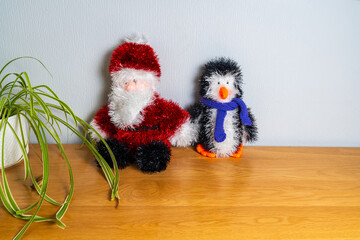 Toy Santa Claus with a woollen penguin and scarf on a table