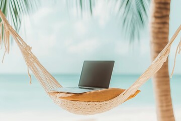 Laptop resting on hammock at tropical beach, palm tree, ocean in background