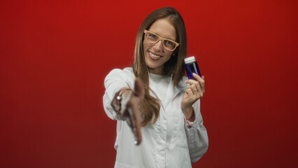 Woman scientist holding blue bottle and extending hand for handshake in red studio; trust outreach...