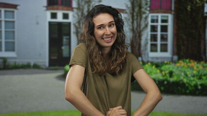 Woman opens palms, shrugs shoulders and smiles softly by brick building entrance outdoors; uncertainty.