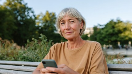 Fototapeta premium Woman sitting on park bench using cell phone.