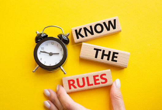 Know the rules symbol. Wooden blocks with words Know the rules. Businessman hand. Beautiful yellow background with alarm clock. Business and Know the rules concept. Copy space.