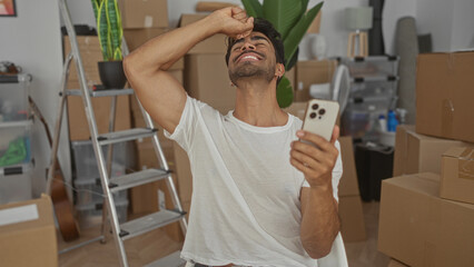 Man holds smartphone and pumps fist in new modern building under renovation; celebration...