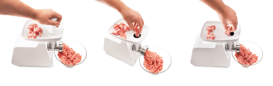 Hands placing raw pork into an electric meat grinder to produce minced meat, isolated on a transparent background.