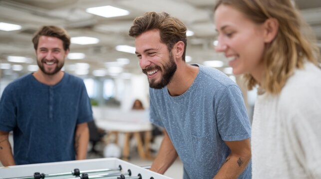 Three people playing foosball in an office setting.