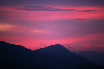 Mountains silhouette under beautiful bright sunset sky with colorful clouds. 