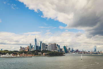 Wide aerial view of the Lower Manhattan skyline with One World Trade Center under dramatic clouds.