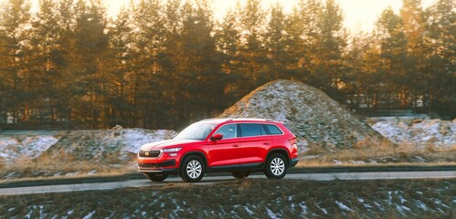 Compact red SUV moving on paved road