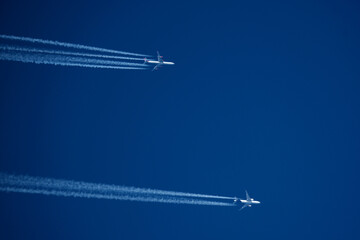 Airplanes in the blue sky. Contrails from two planes flying side by side