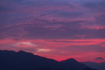 Mountains silhouette under beautiful bright sunset sky with colorful clouds. 