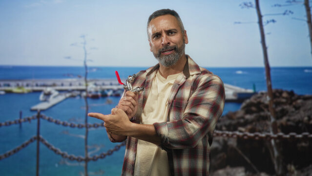 Man holding a faucet points finger toward a port pier near boats and seaside while gripping the valve; repair confidence.