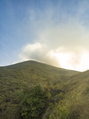 The view during a morning hike or sunrise on Mount Penanggungan is beautiful. It offers a vast landscape, including savannahs and ancient buildings like temples.