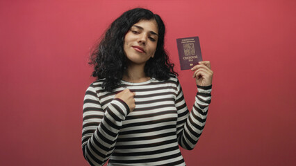 Young brunette woman holding czech passport and hand to chest in red studio; confidence travel aspiration.