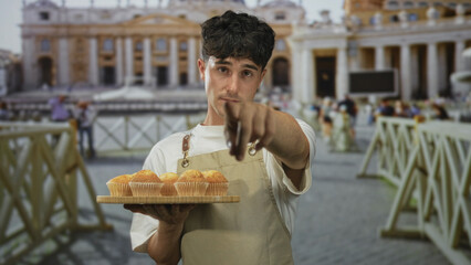 Man points finger while offering muffins on a wooden tray in a historic building at st peter's...