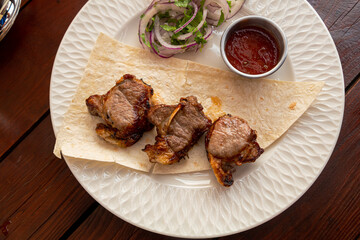 Lamb apple shashlik with fried tomato sauce and lavash on a white plate. Horizontal photo