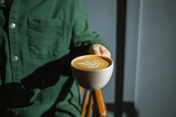 Close-up of a man enjoying a cappuccino in the morning sunshine at a cafe.