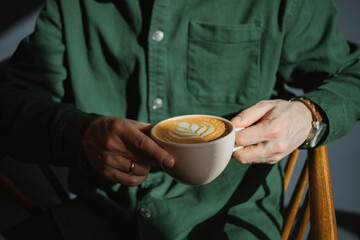 Close-up of a man enjoying a cup of coffee in the morning light at a cafe.