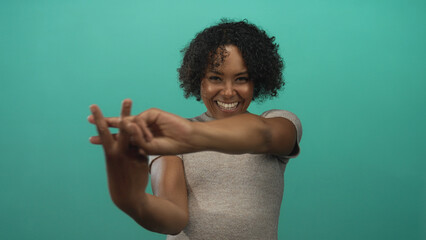 Young african american woman smiling makes hashtag gesture in a professional studio; social connection joy.