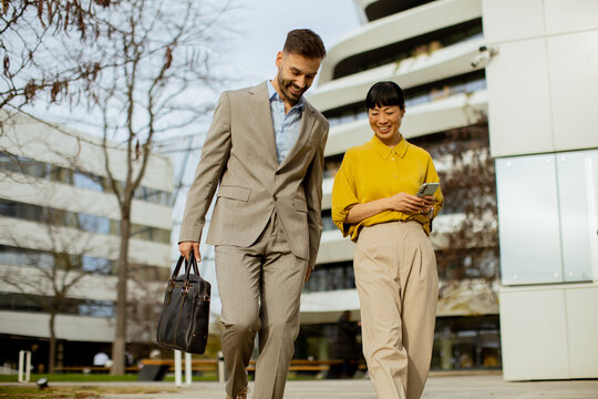 Two professionals walking together outside a modern building on a sunny day