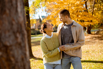 Couple enjoys a sunny autumn day surrounded by colorful leaves in a peaceful park setting