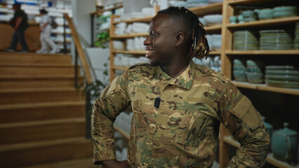 Man soldier in camouflage uniform smiling with hands on hips and dogtag in home decor shop; pride duty.